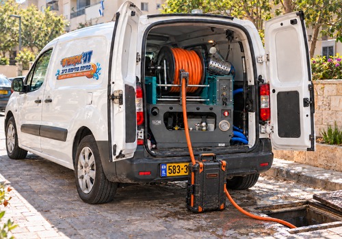 המחשה של רכב שירות עם ציוד לשטיפת קווי ביוב וצינור המוביל לפתח ביקורת
